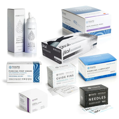 Threadless Piercing Studio Essentials Bundle featuring several piercing products on a white background, with Tanto guide pins, 16G piercing needles, drapes, lubricant, prep swabs, skin markers, Steripierce saline and black nitrile gloves